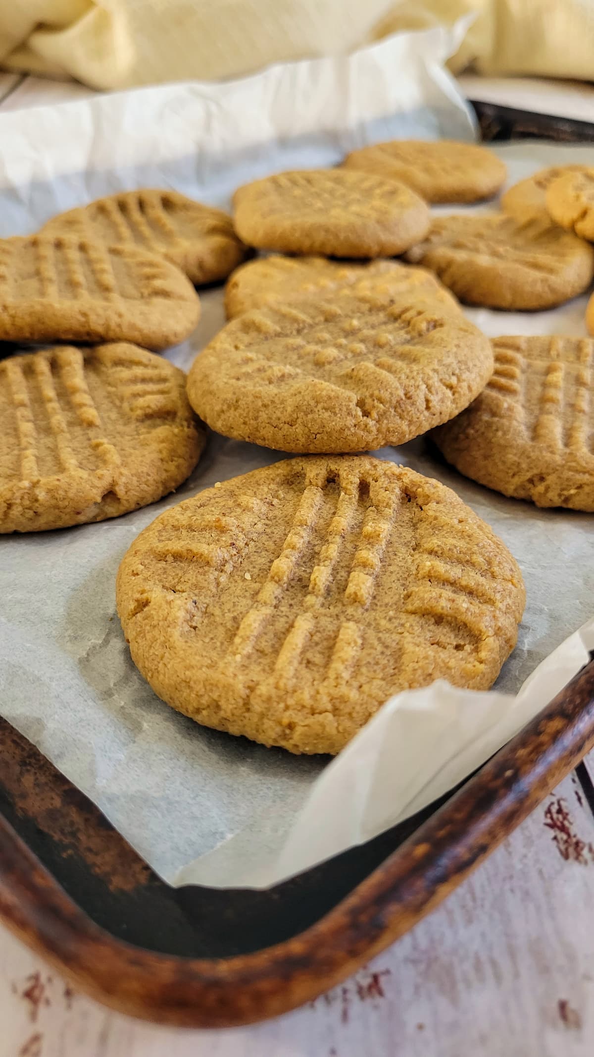 peanut butter cookies piled on top of each other on a parchment lined baking sheet