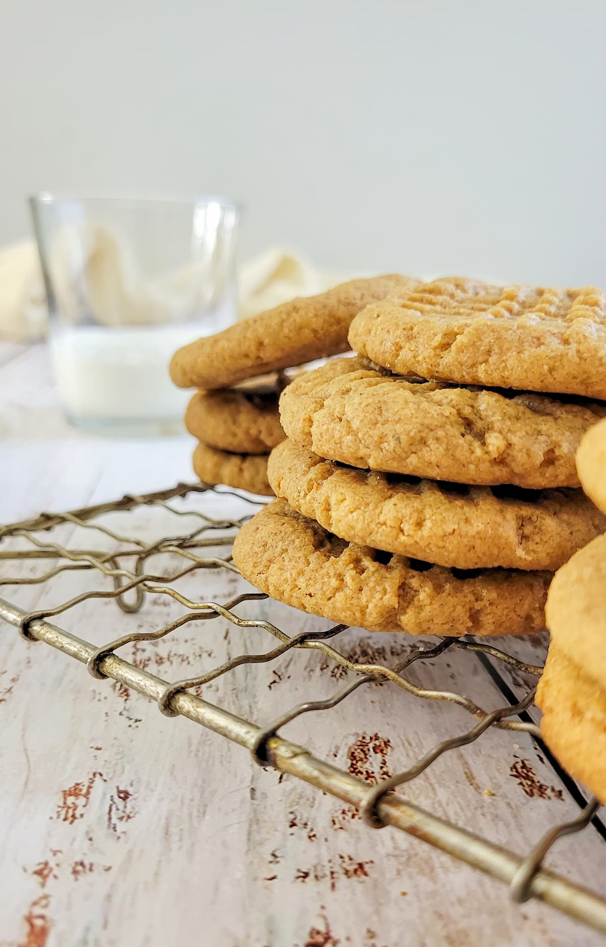 cookies stacked on a wire rack with a glass of milk in the background