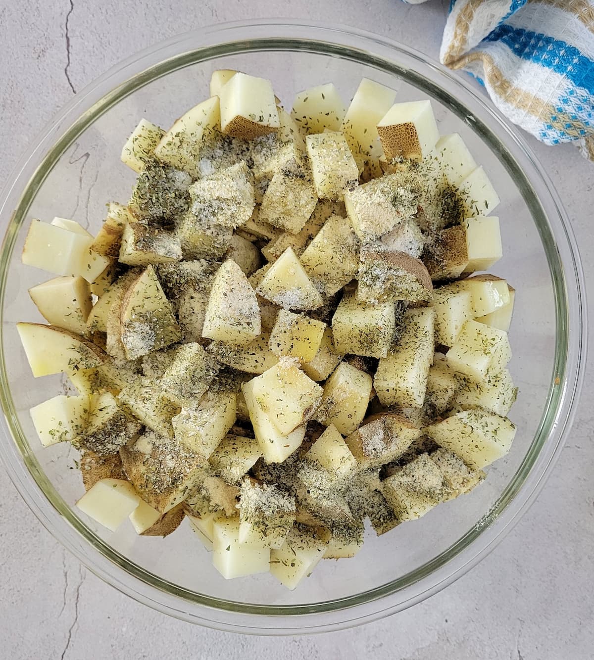 bowl of raw cubed potatoes with seasonings on top