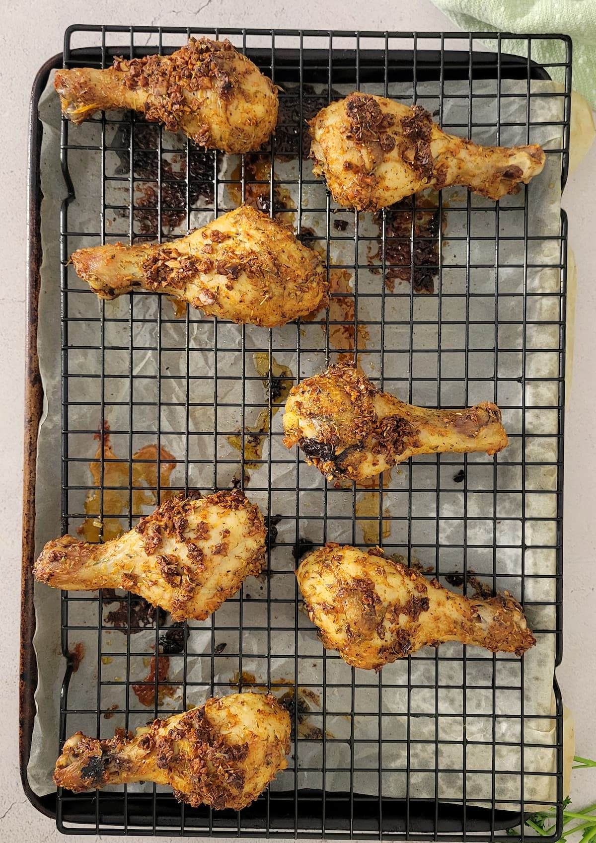 cooked chicken drumsticks on a wire rack on a parchment lined baking sheet