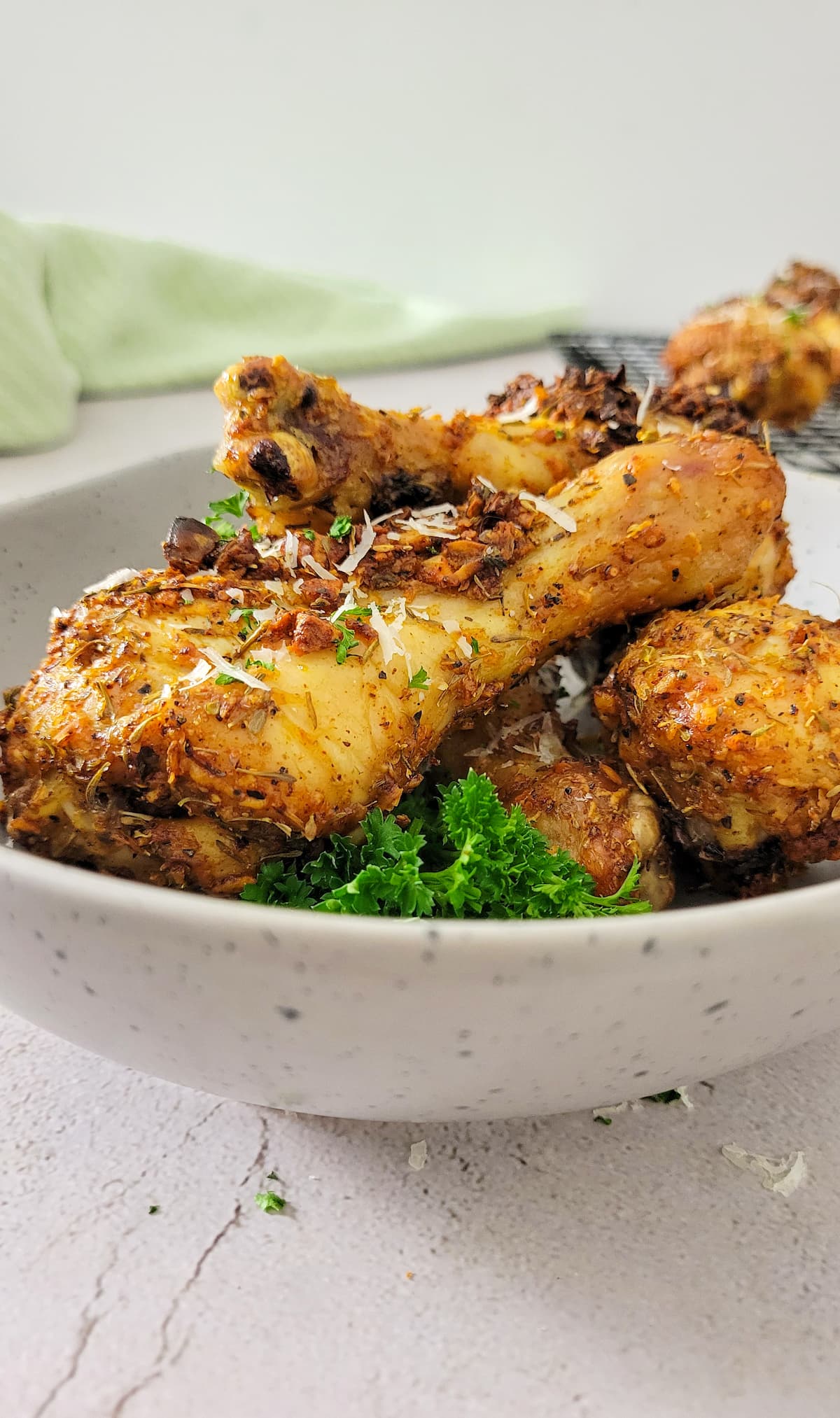 baked chicken drumsticks in a bowl garnished with fresh parsley and parmesan cheese