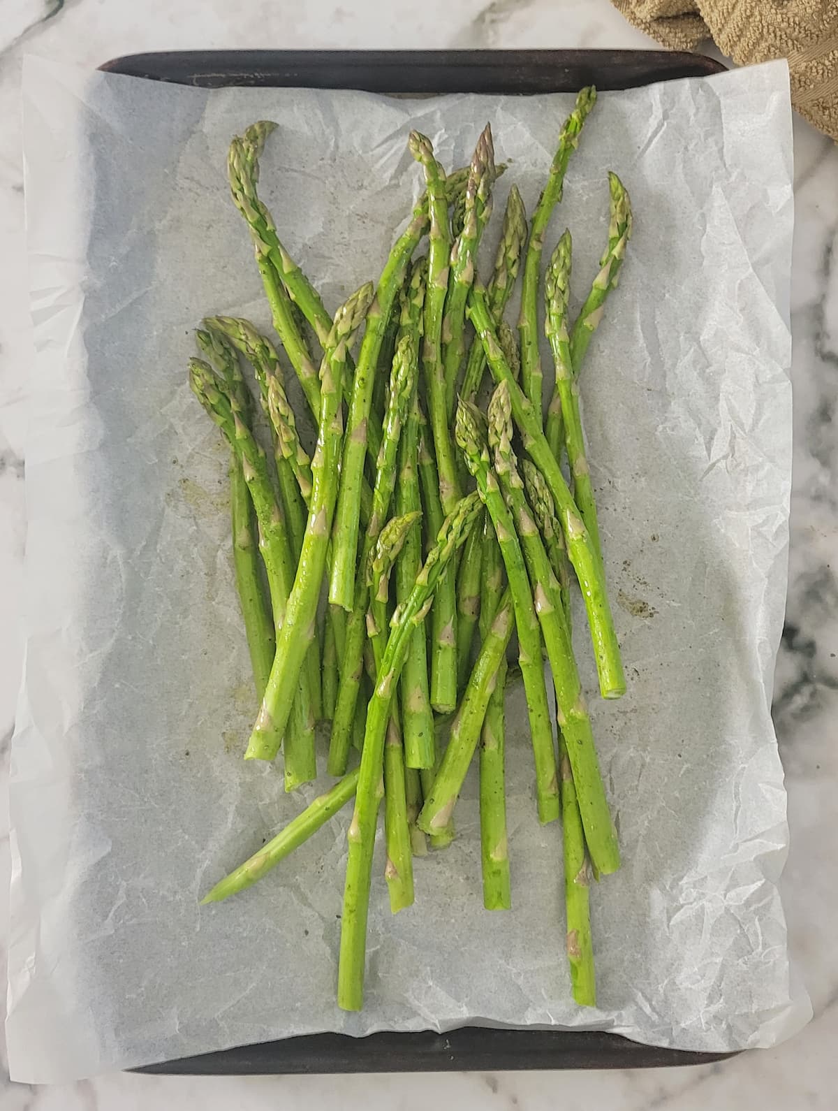 bunch of raw asparagus on a parchment lined baking sheet