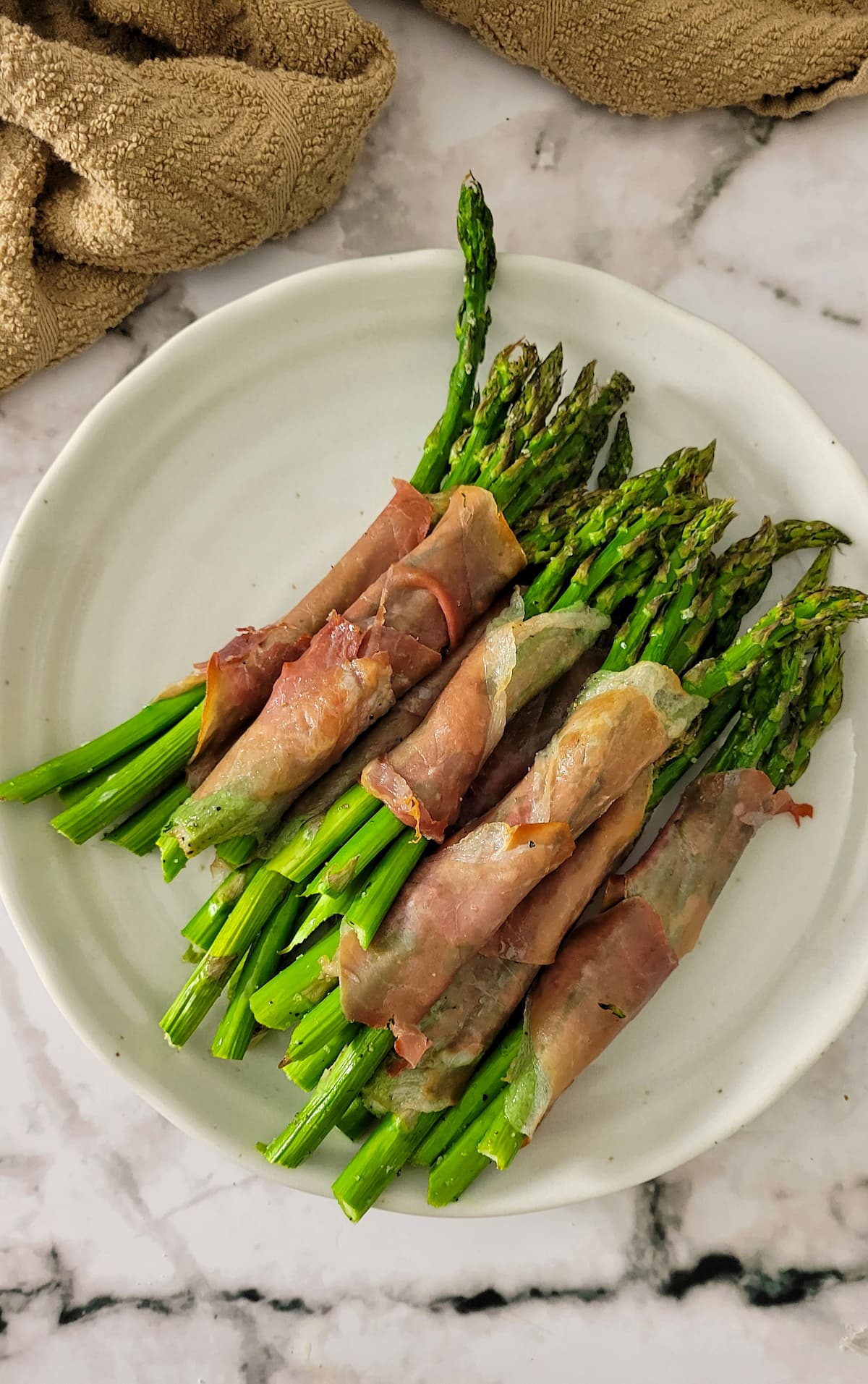 prosciutto wrapped asparagus bundles on a plate