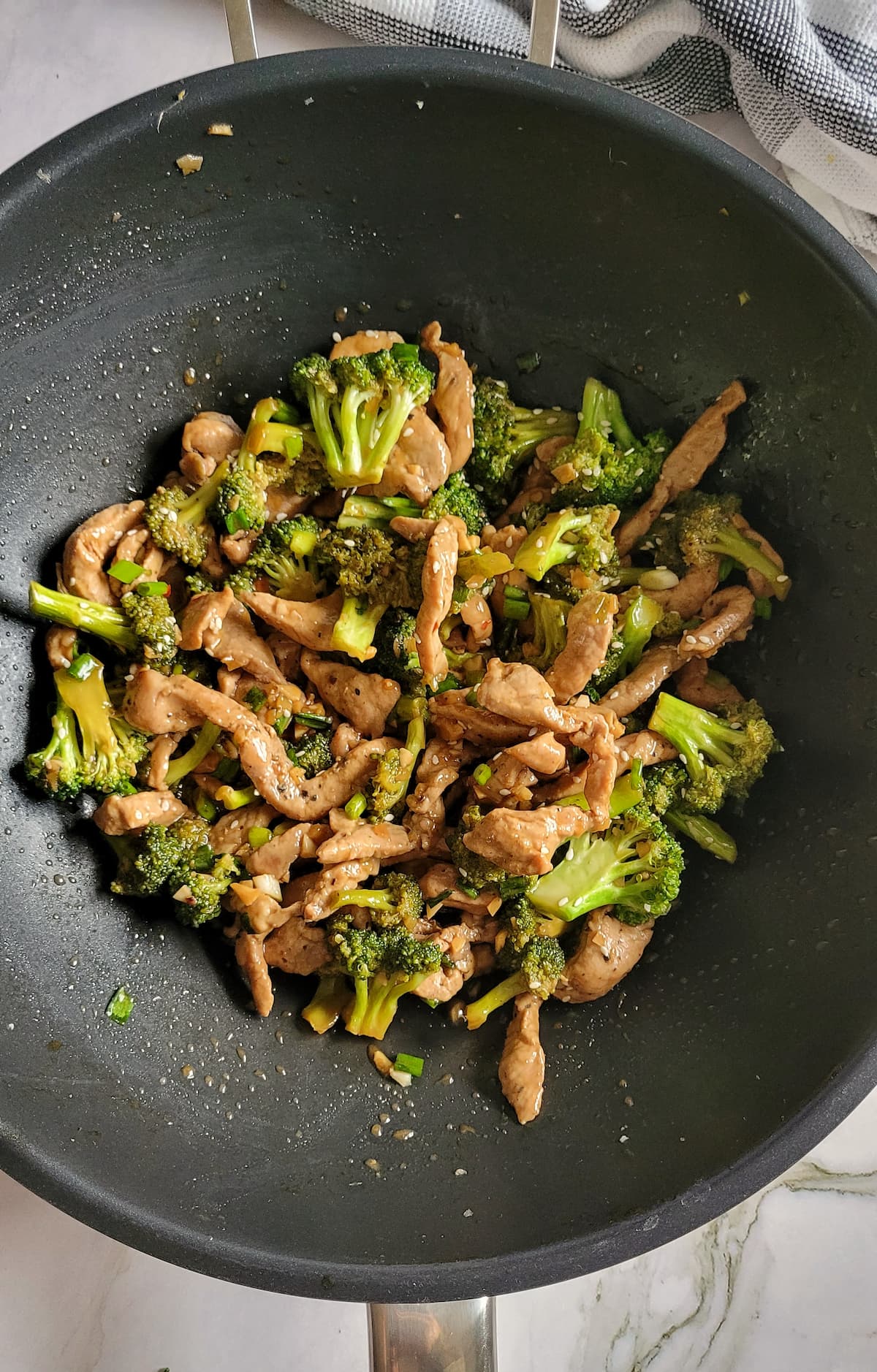 cooked broccoli florets and pork strips in a wok