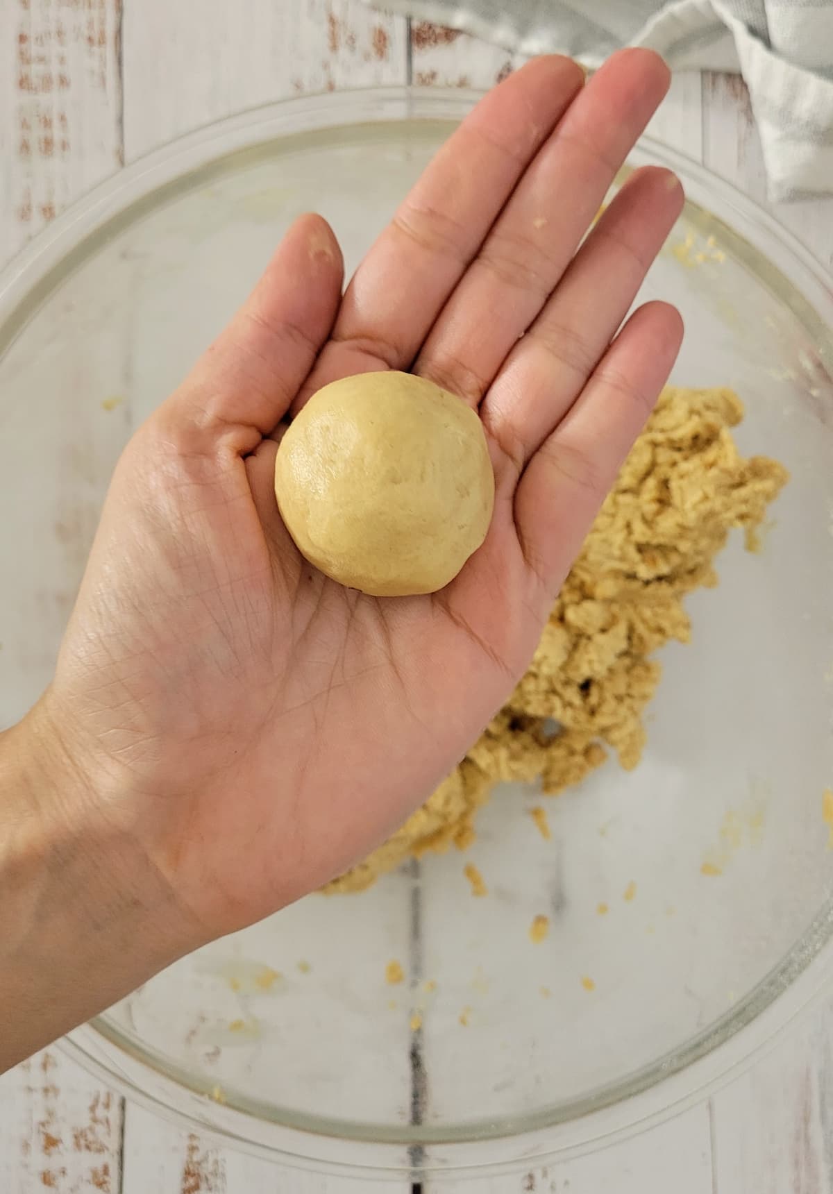 hand holding a peanut butter ball over a bowl