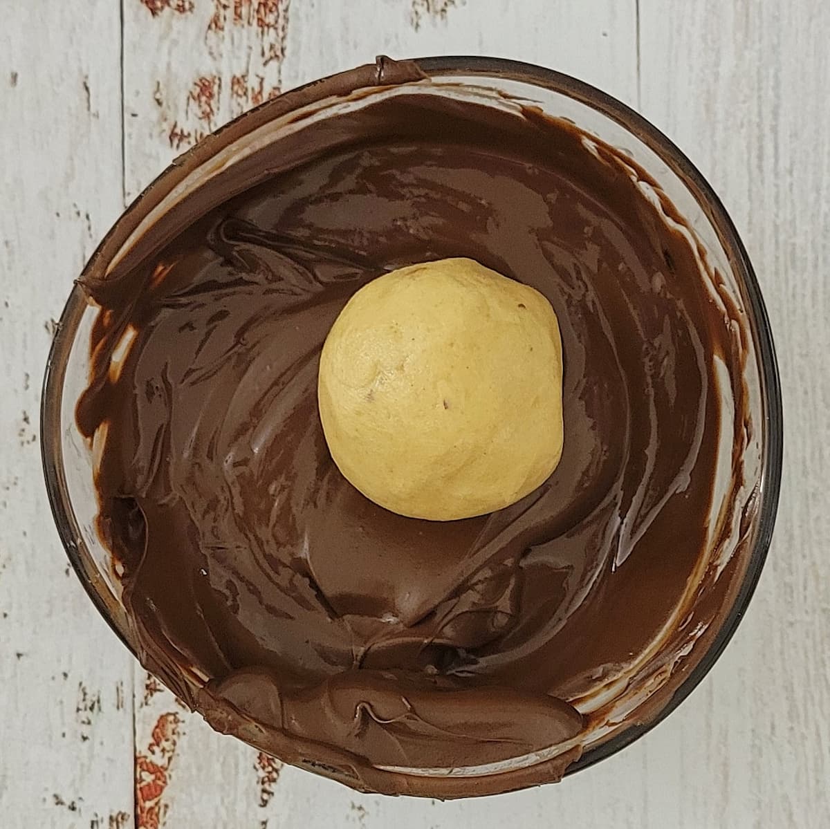 peanut butter ball in a bowl of melted chocolate