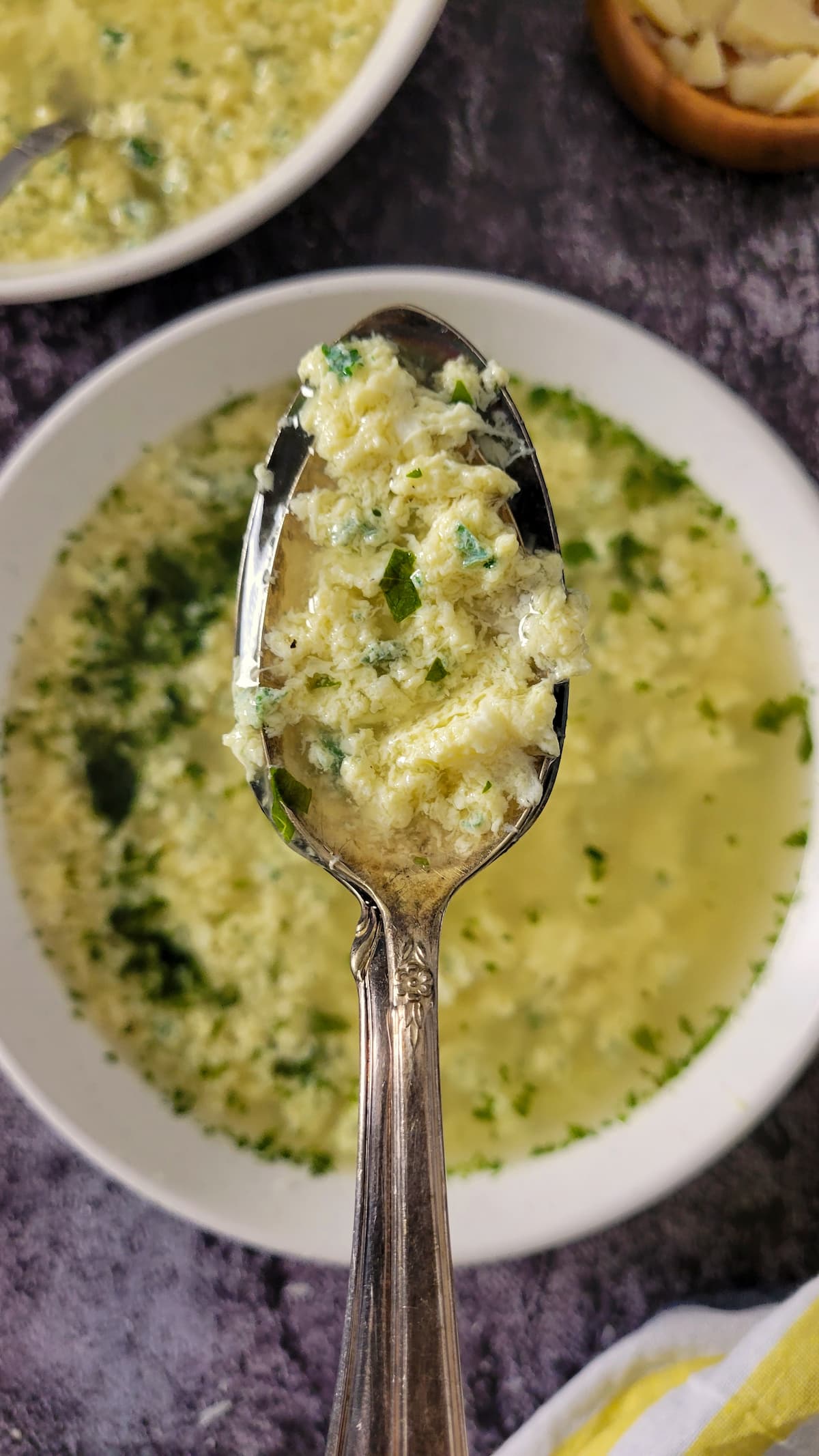 spoonful of egg drop soup with parsley over a bowl with the rest of it