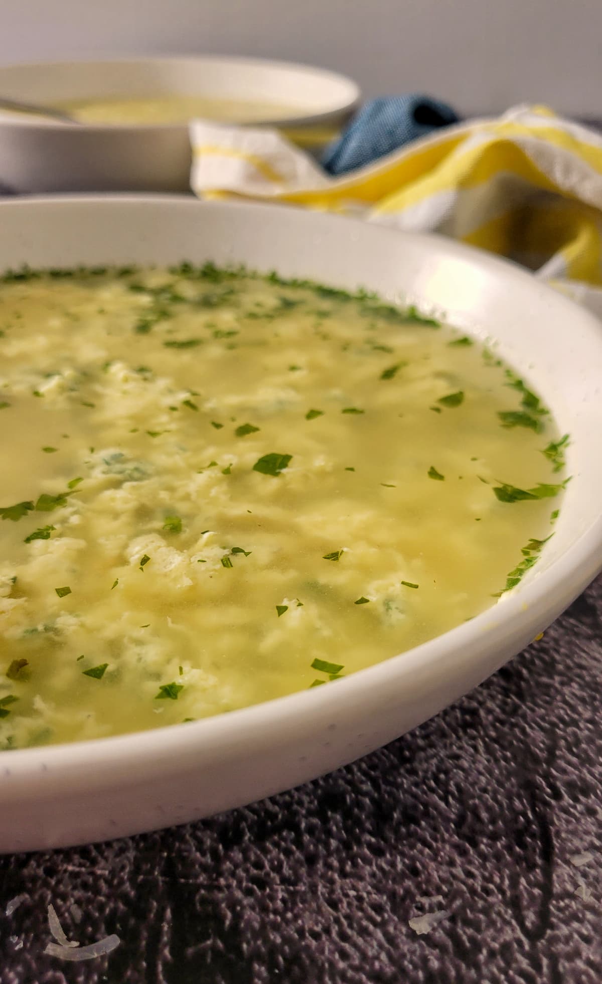 side view of egg drop soup with chopped fresh parsley in a bowl