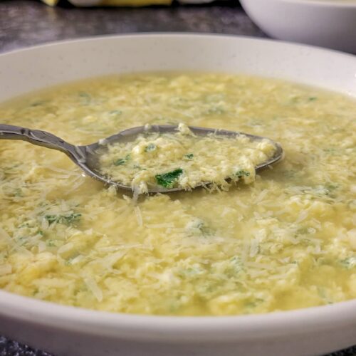 egg drop soup with parsley in a bowl with a spoon