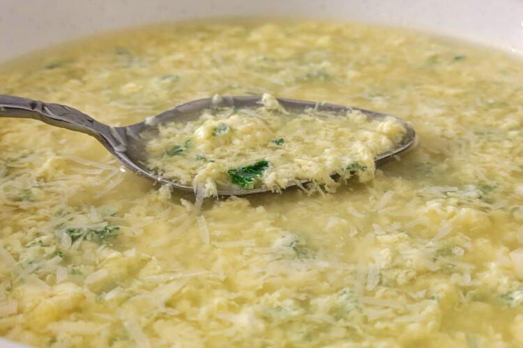 egg drop soup with parsley in a bowl with a spoon