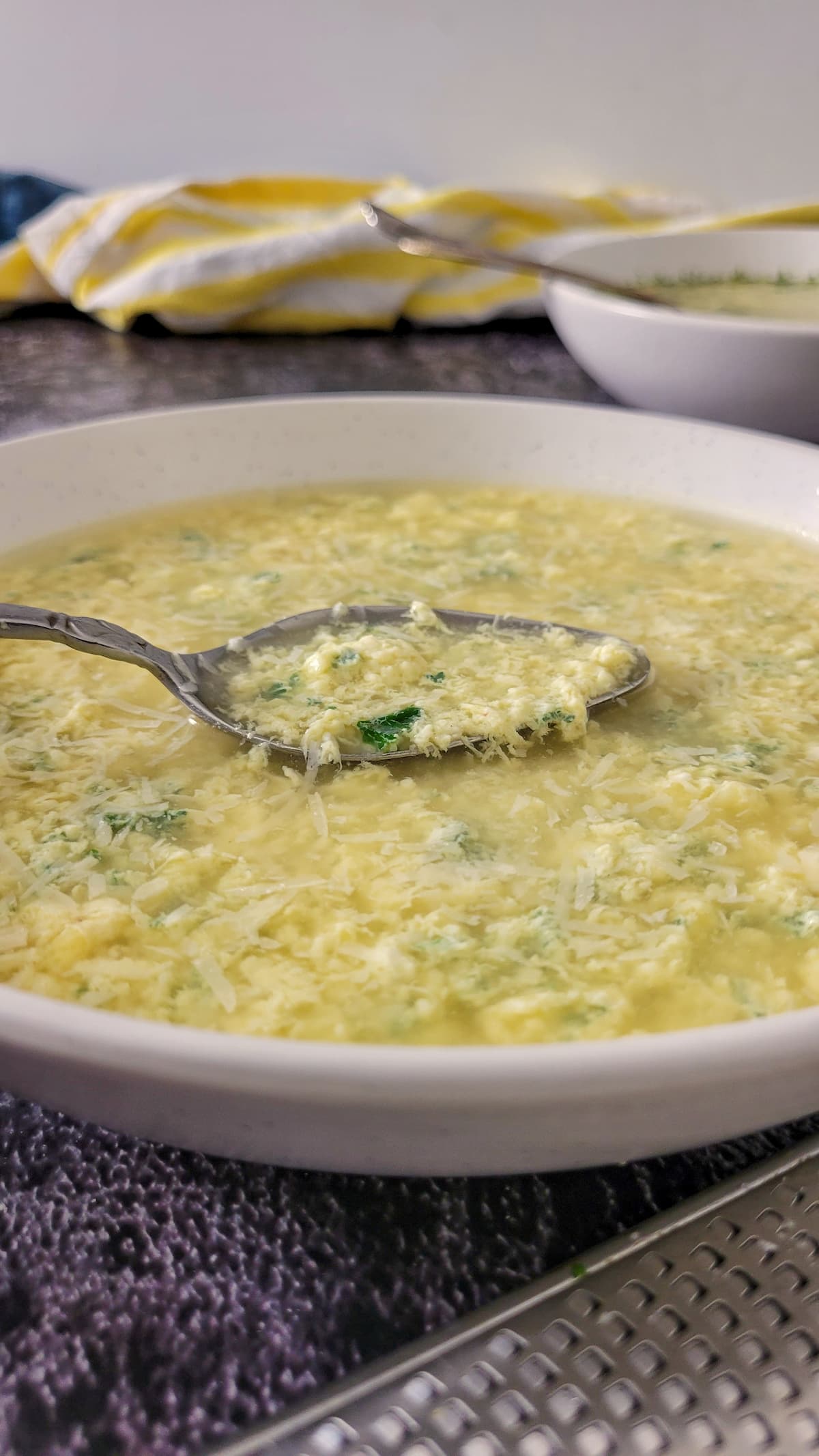 egg drop soup with parsley in a bowl with a spoon