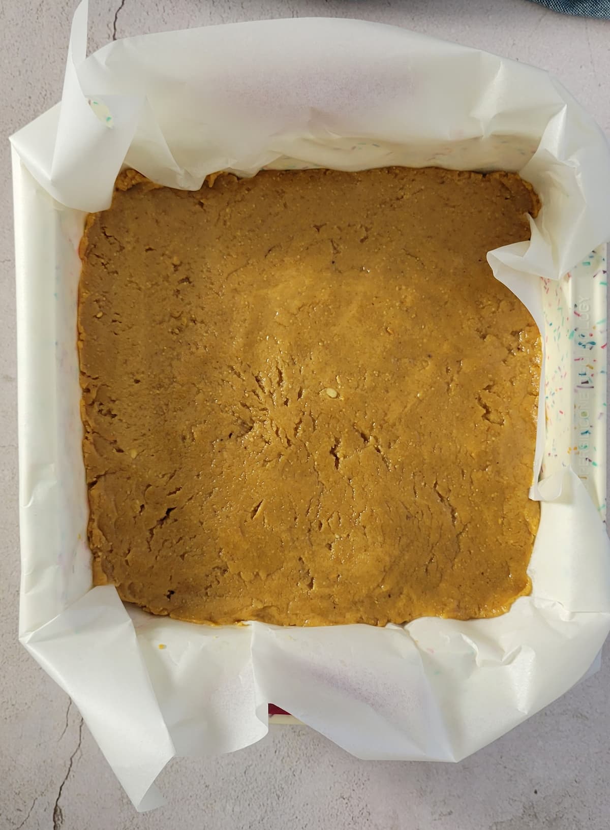 uncut peanut butter fudge in a parchment lined pan