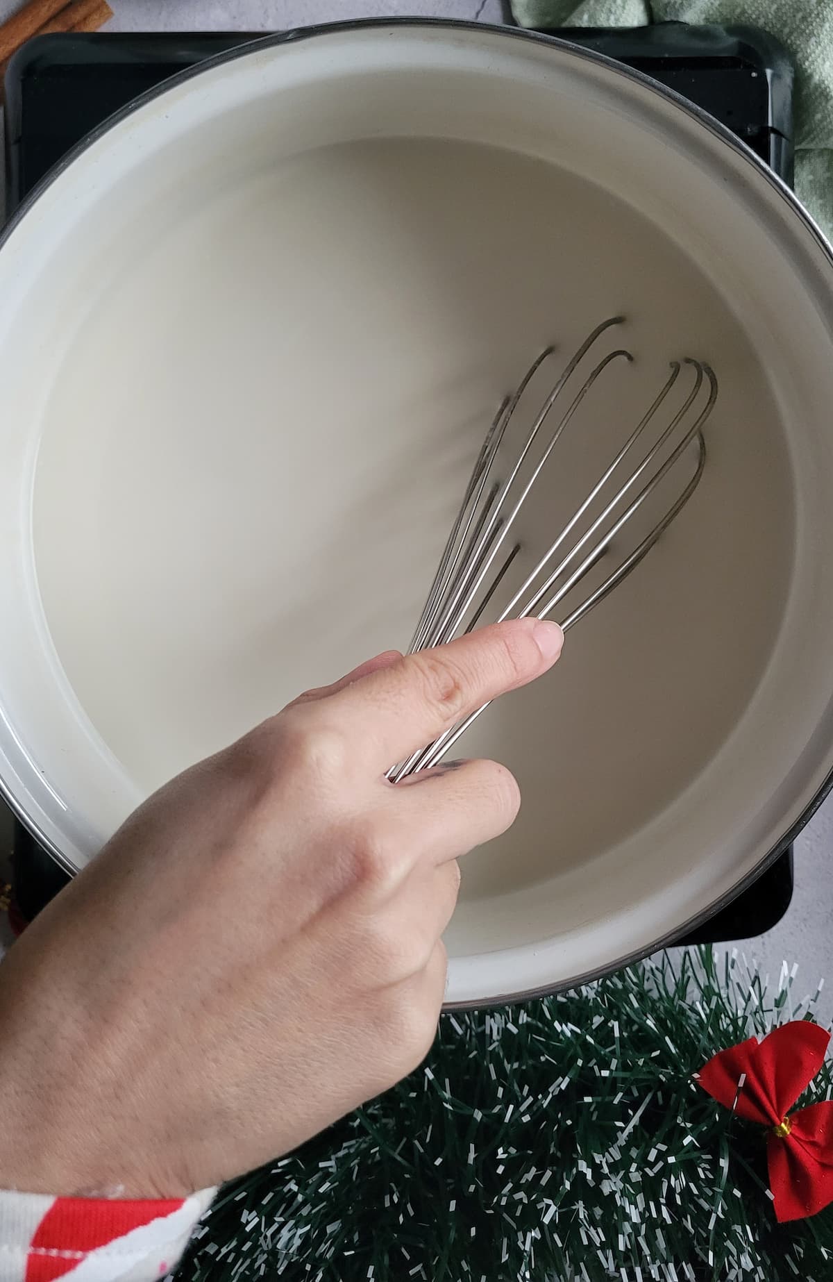 hand whisking milk in a pot
