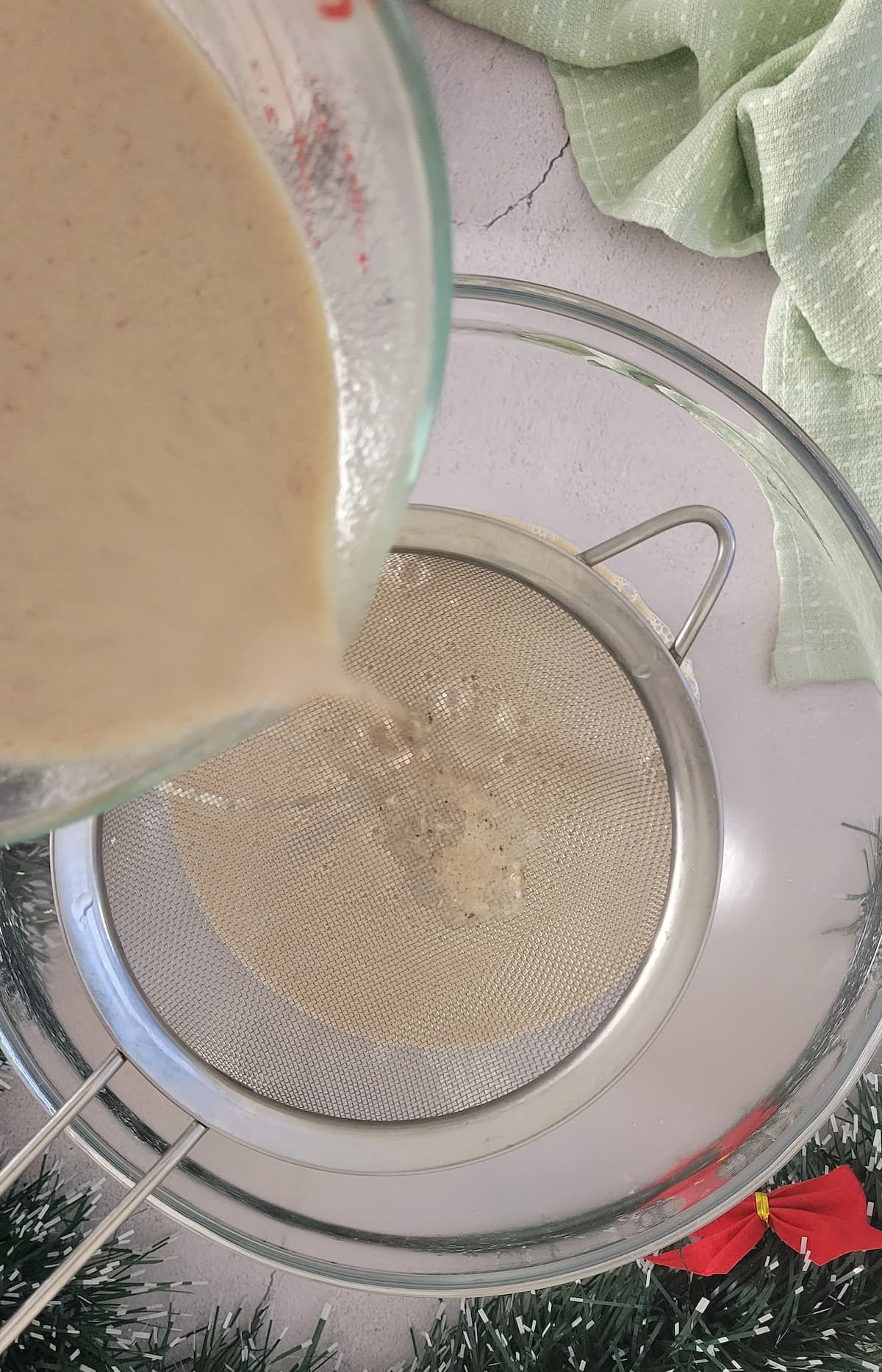 eggnog being poured into a fine mesh strainer over a bowl