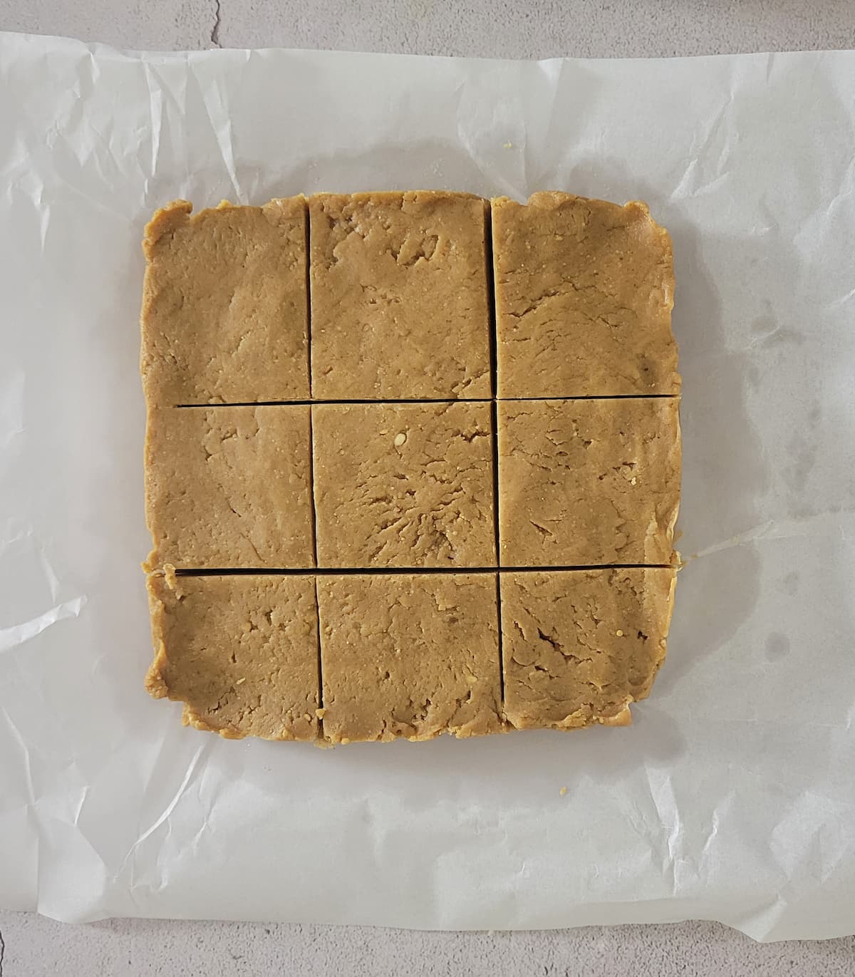 peanut butter fudge cut into squares on a piece of parchment paper