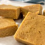 peanut butter fudge stacked on a piece of parchment paper