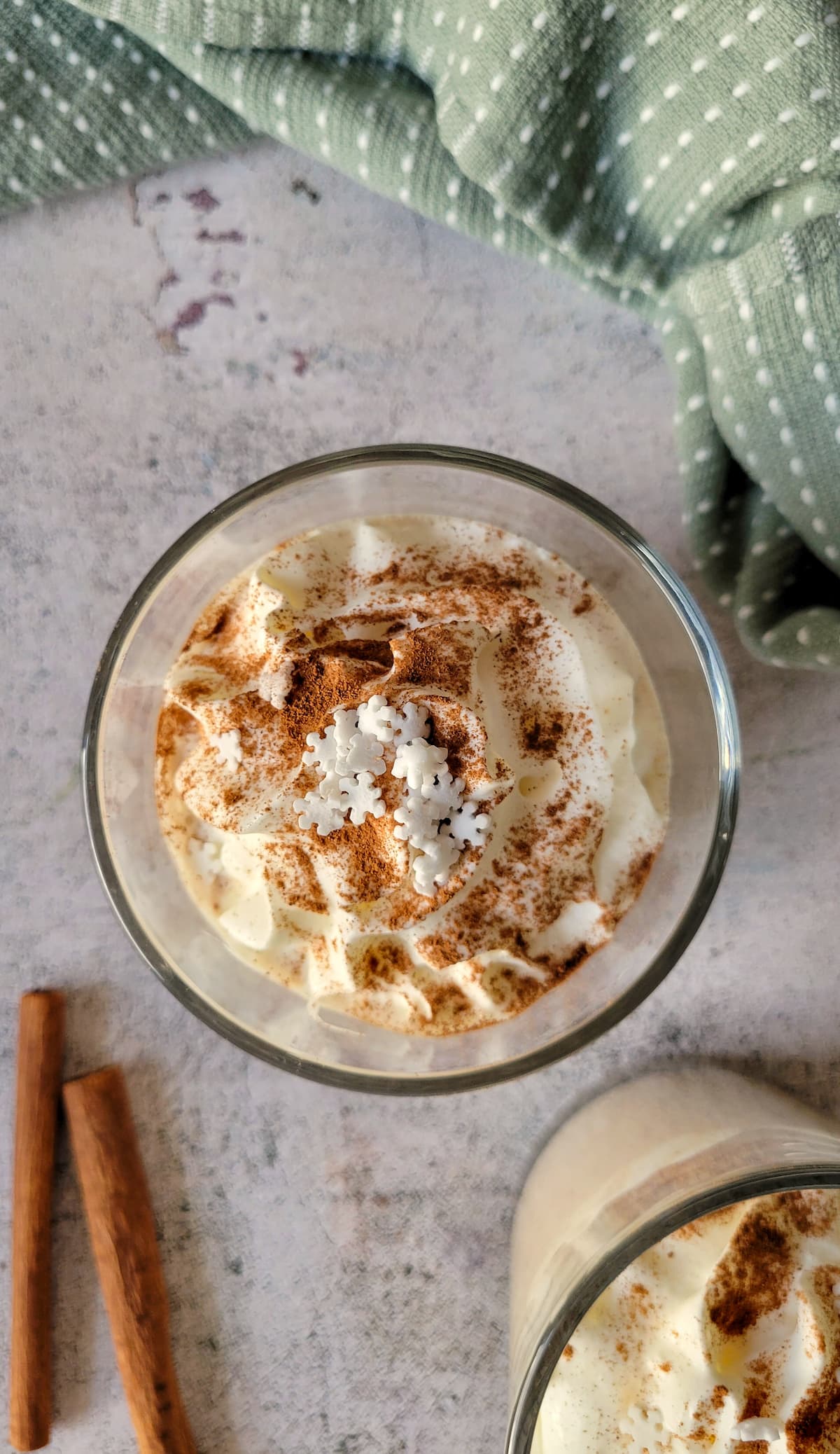 glass of eggnog with whipped cream, snowflake sprinkles and cinnamon