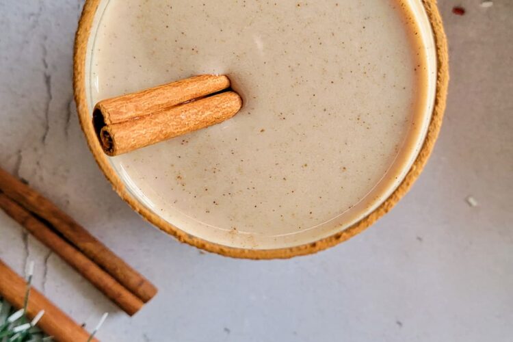 glass of eggnog with a cinnamon stick and rim