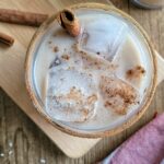 rum and eggnog cocktail garnished with a cinnamon stick and sprinkled cinnamon