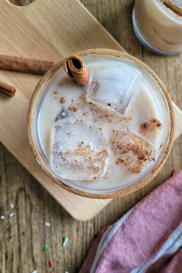 rum and eggnog cocktail garnished with a cinnamon stick and sprinkled cinnamon
