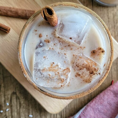 rum and eggnog cocktail garnished with a cinnamon stick and sprinkled cinnamon