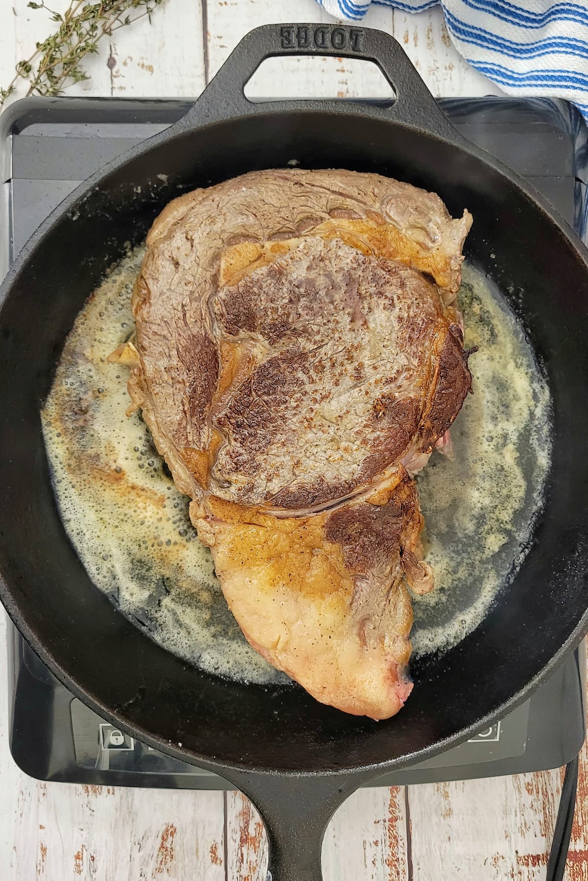 ribeye steak cooking in butter in a cast iron skillet