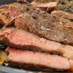 slices of medium rare steak in a cast iron skillet with maldon sea salt, fresh thyme in the background
