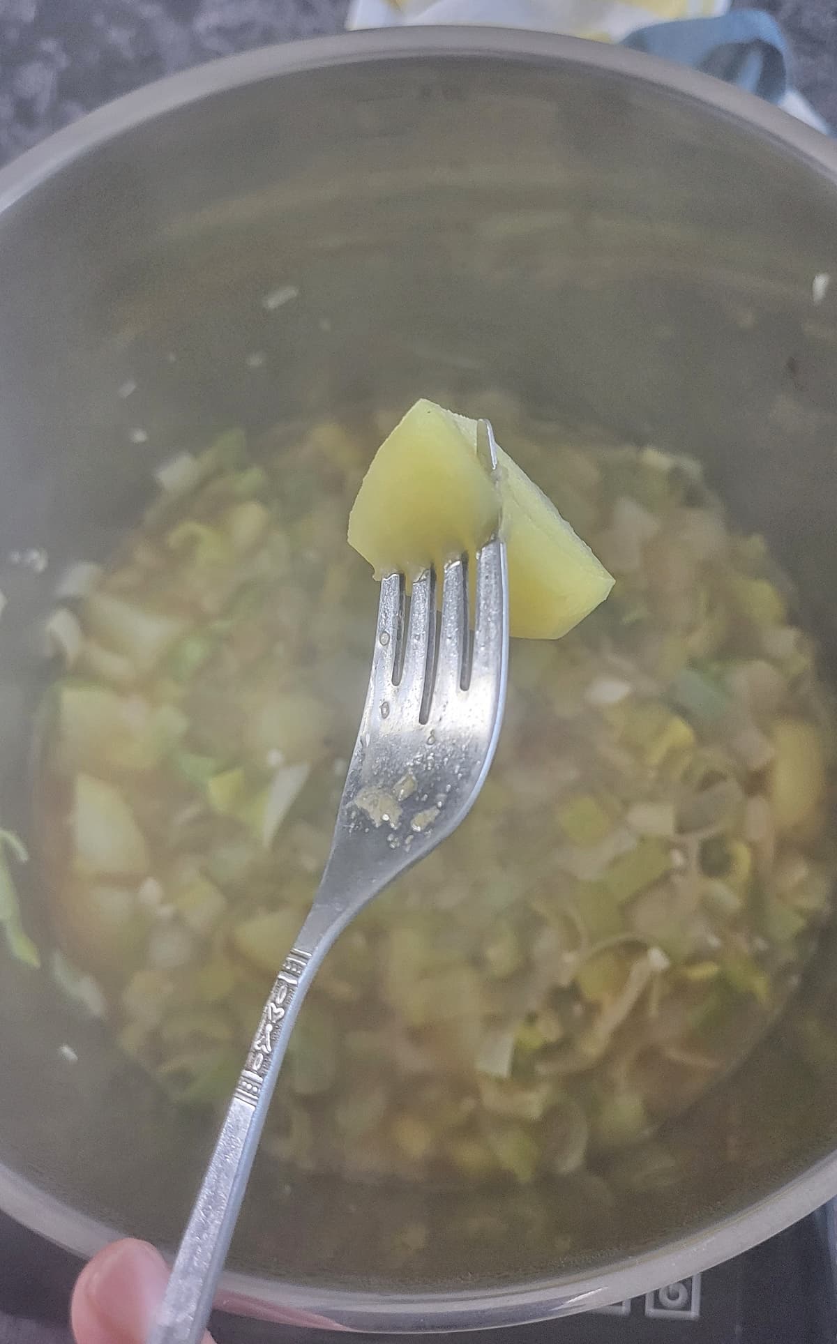 fork piercing a chunk of potato over a pot with more