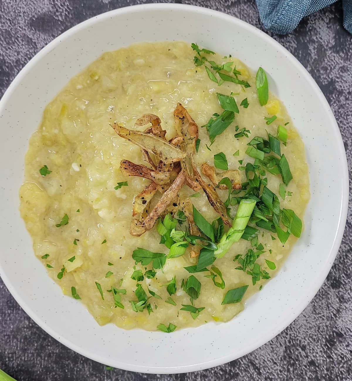bowl of potato leek soup garnished with crispy potato peels, green onions and parsley