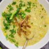 bowl of potato leek soup with chopped green onions, parsley and potato peels