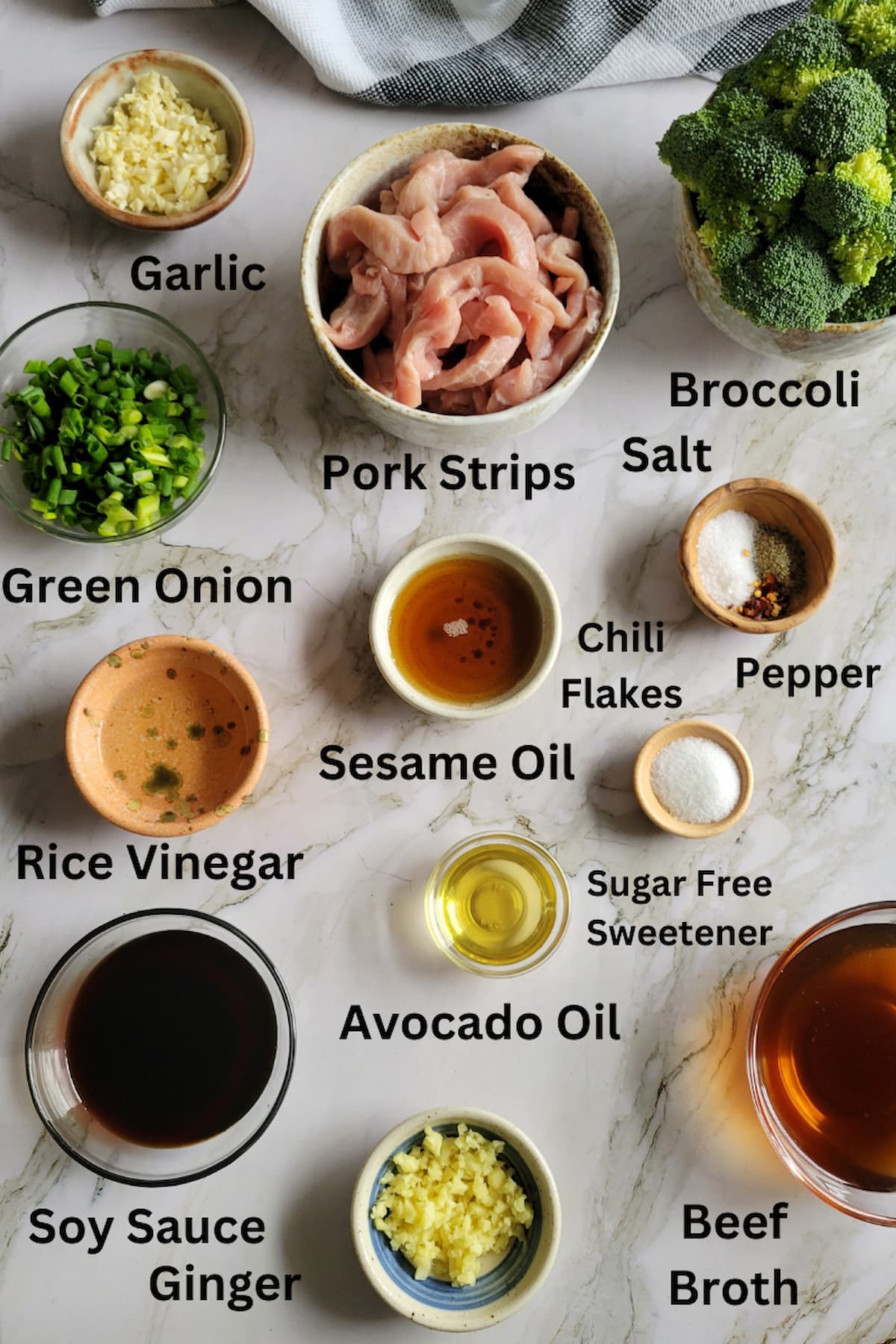 ingredients for broccoli and pork - pork strips, broccoli, garlic, ginger, soy sauce, sesame oil, avocado oil, salt, pepper, rice vinegar, green onion, sugar free sweetener, beef broth, chili flakes