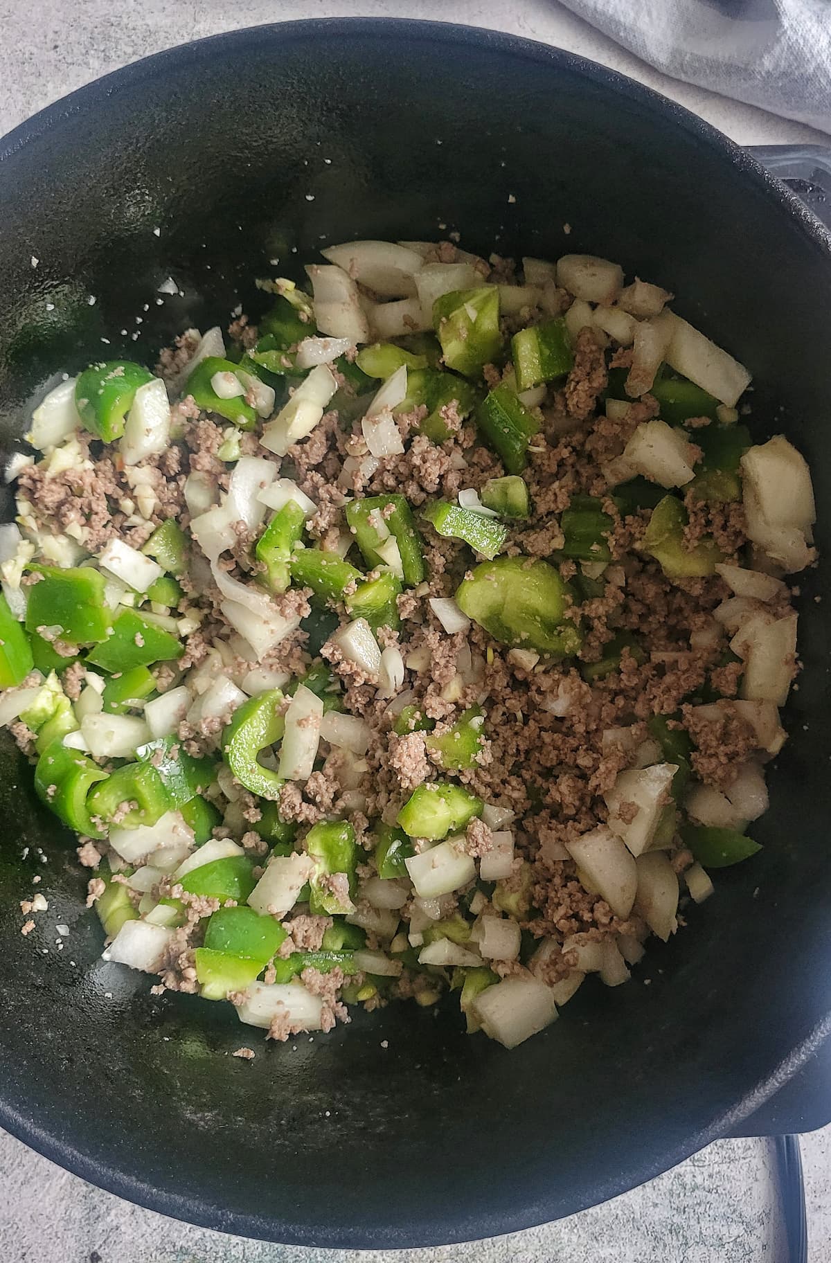 browned ground beef, diced green peppers and diced onions in a pot