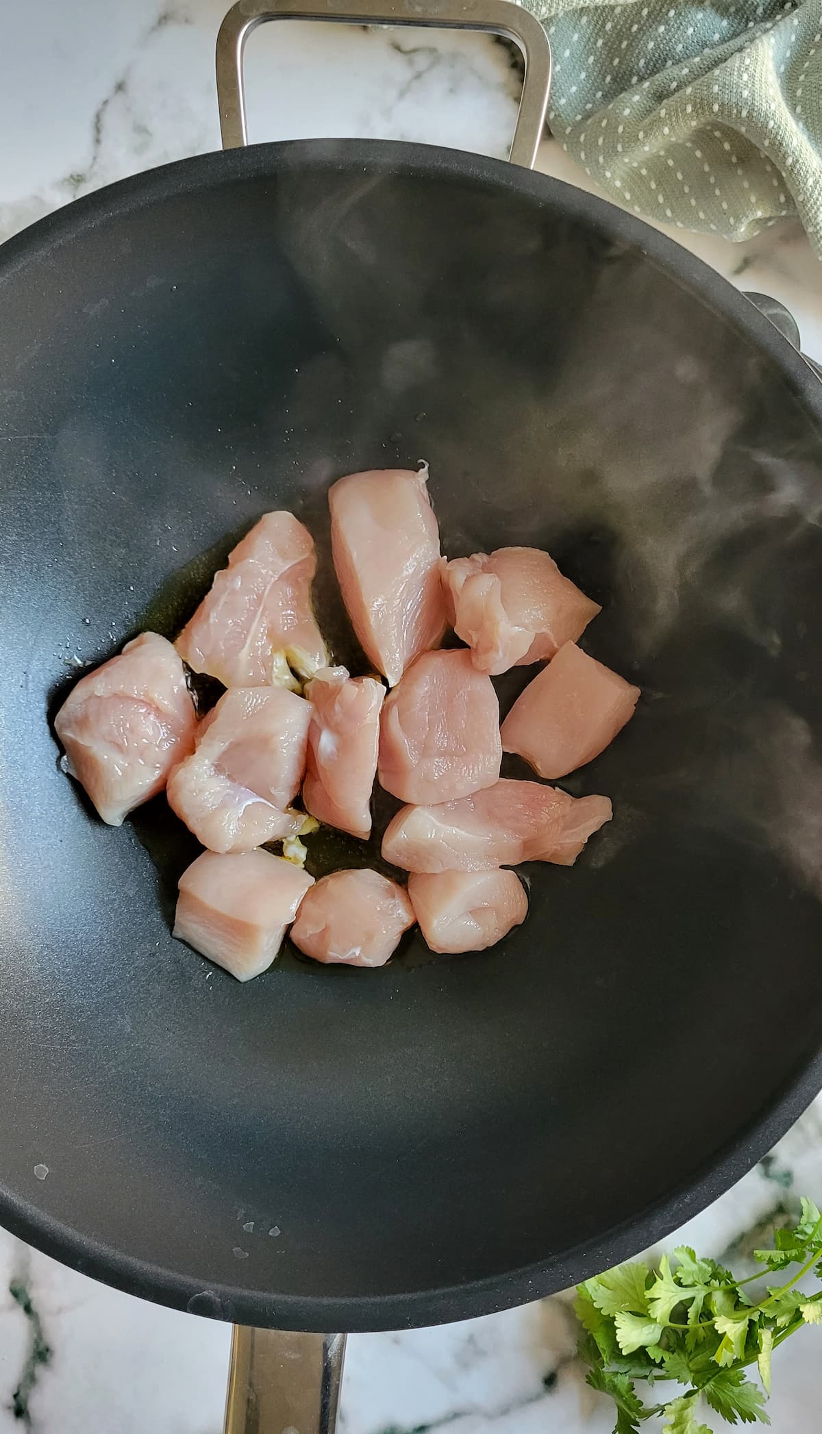 raw cubed chicken cooking in a wok