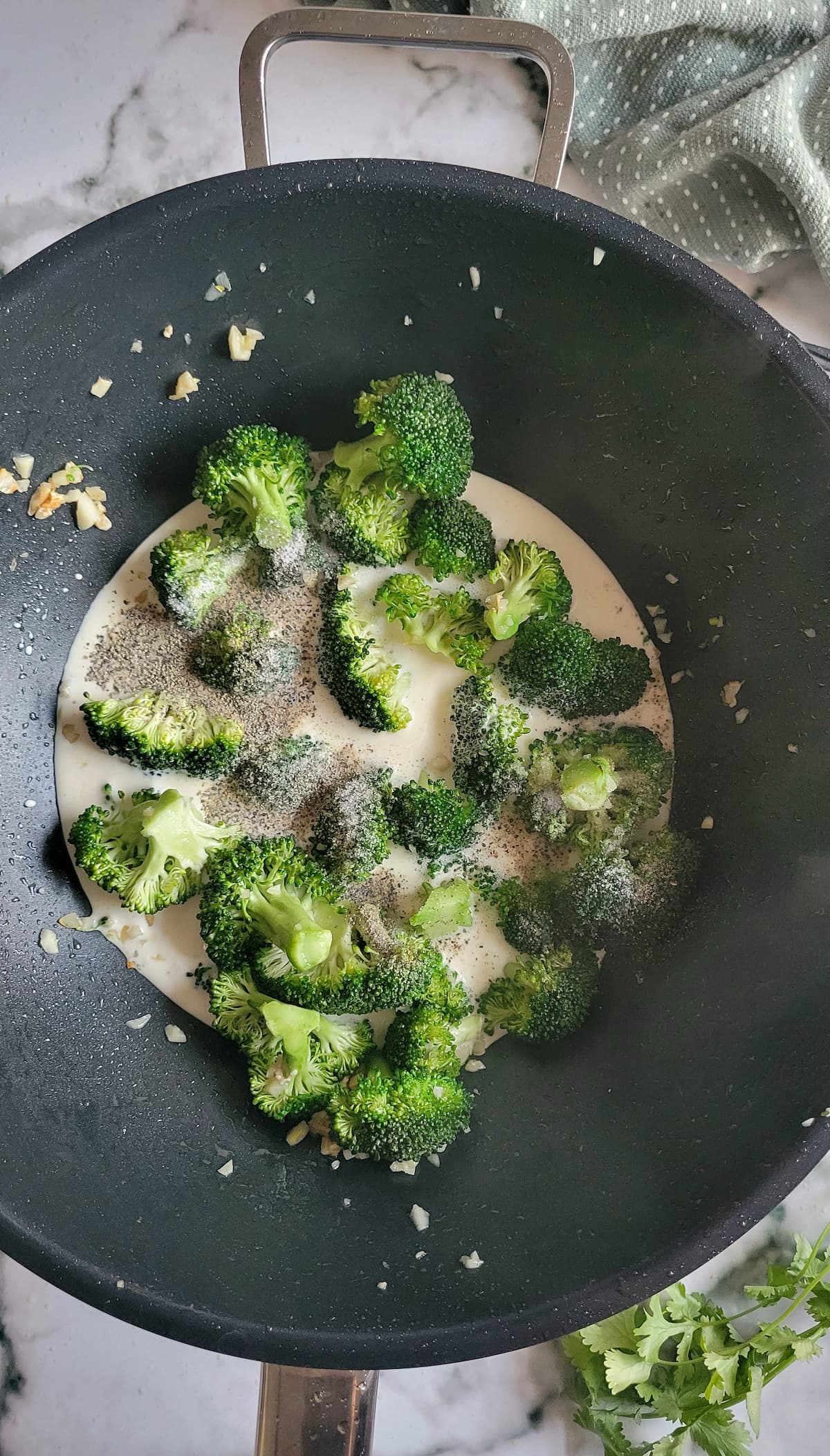broccoli florets, pepper and garlic in a creamy sauce in a wok