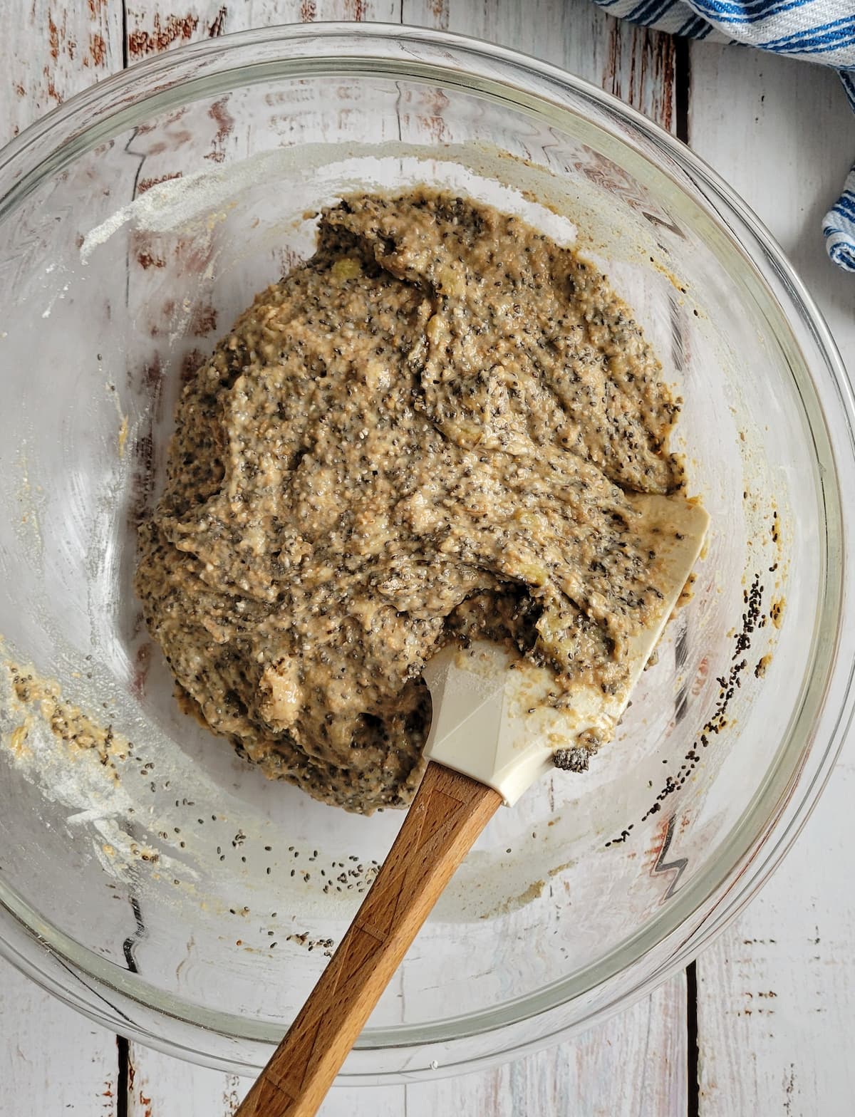 rubber spatula in a bowl with brown batter and chia seeds