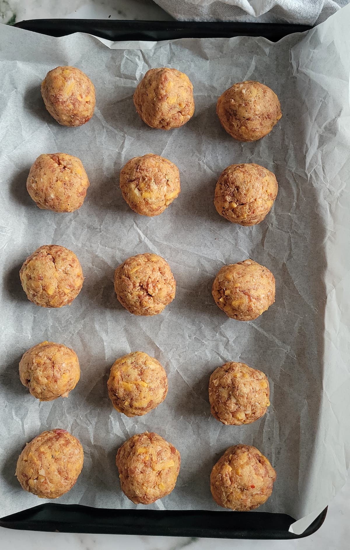 raw sausage balls on a parchment lined baking sheet