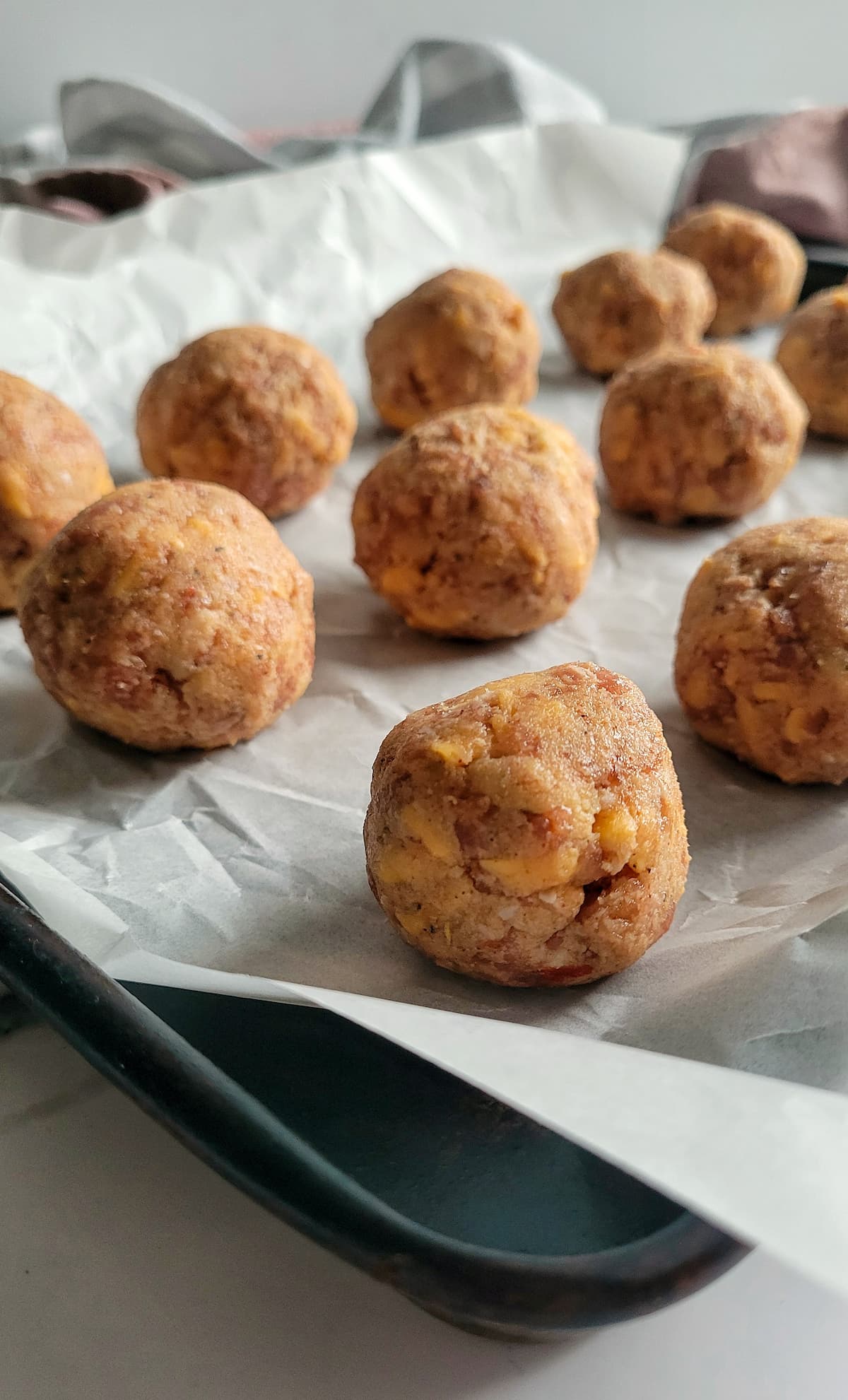 raw sausage balls on a parchment lined baking sheet