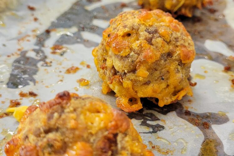4 cooked sausage balls on a parchment lined baking sheet