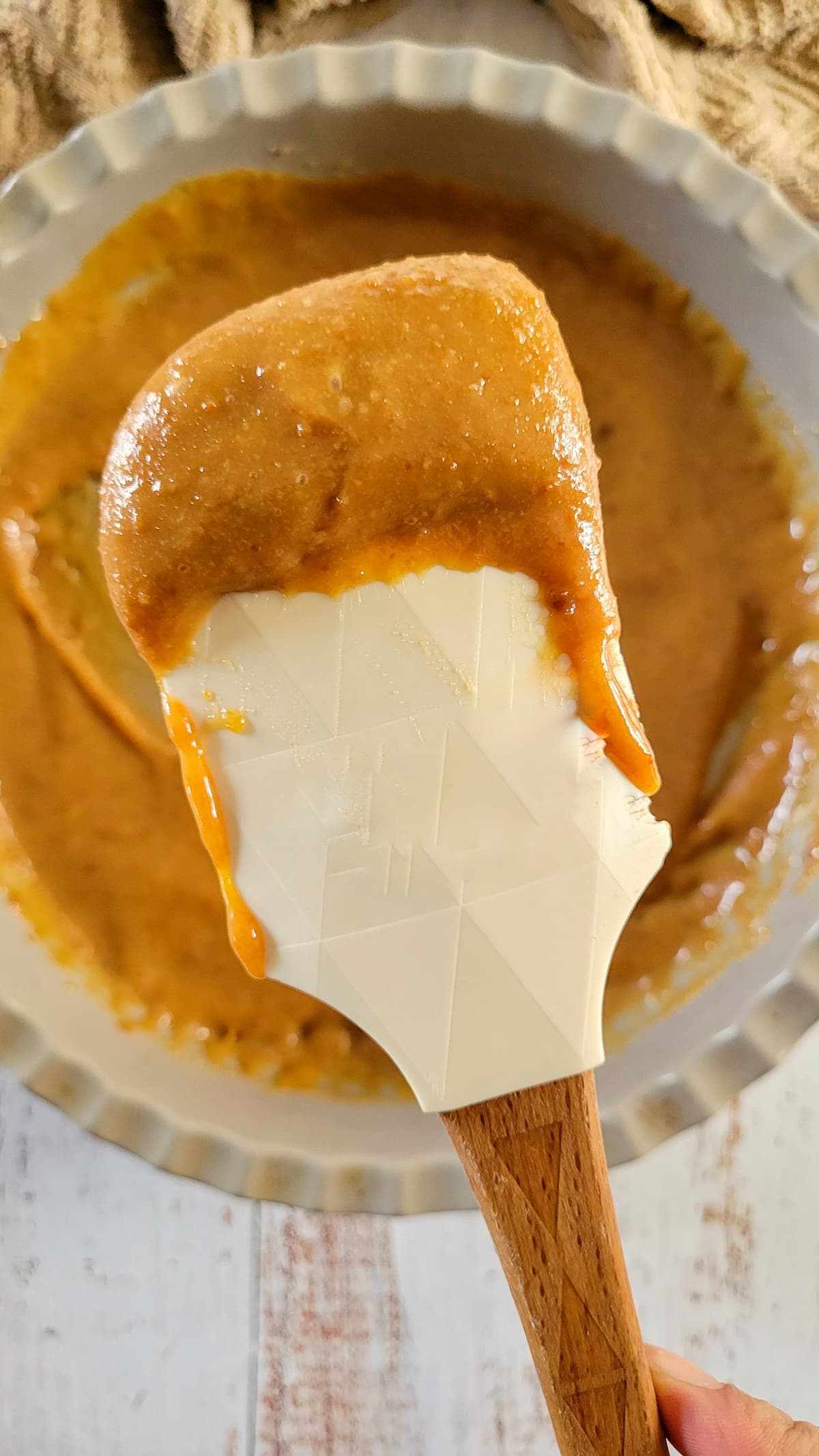 caramel sauce on a rubber spatula over a dish with more