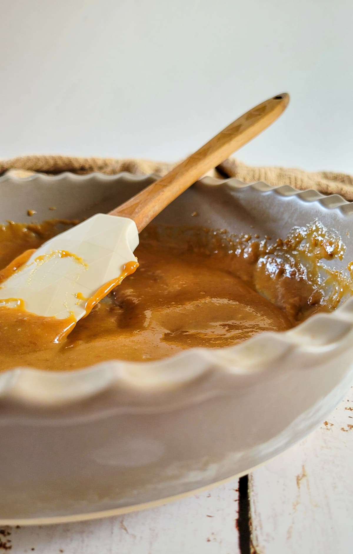 side view of homemade caramel sauce in a dish with a rubber spatula