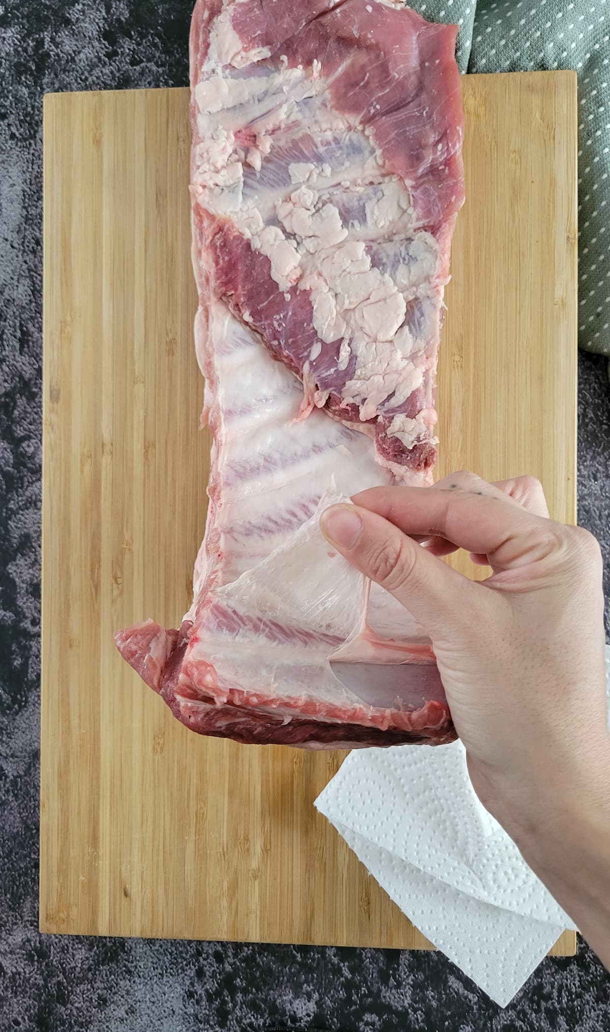 hand removing the membrane off a rack of ribs