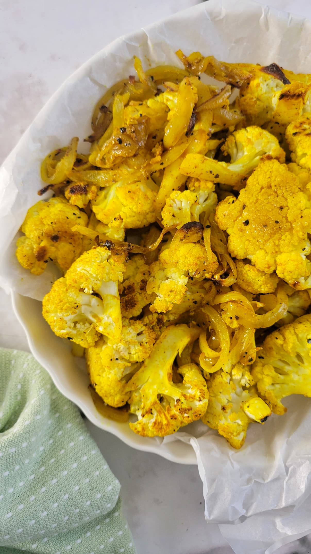bowl of yellow baked cauliflower with onions