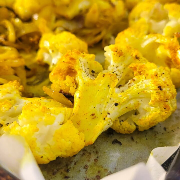 baked yellow cauliflower on a parchment lined baking sheet