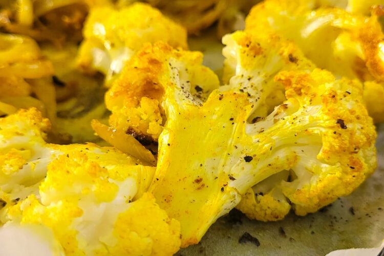 baked yellow cauliflower on a parchment lined baking sheet