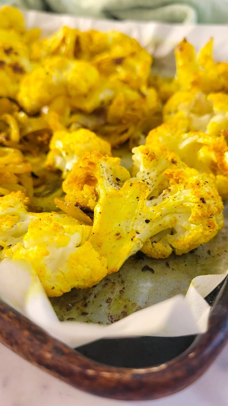 yellow cauliflower on a parchment lined baking sheet