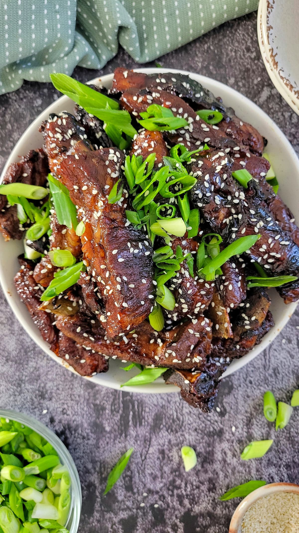 bowl of sticky asian ribs with green onions and sesame seeds