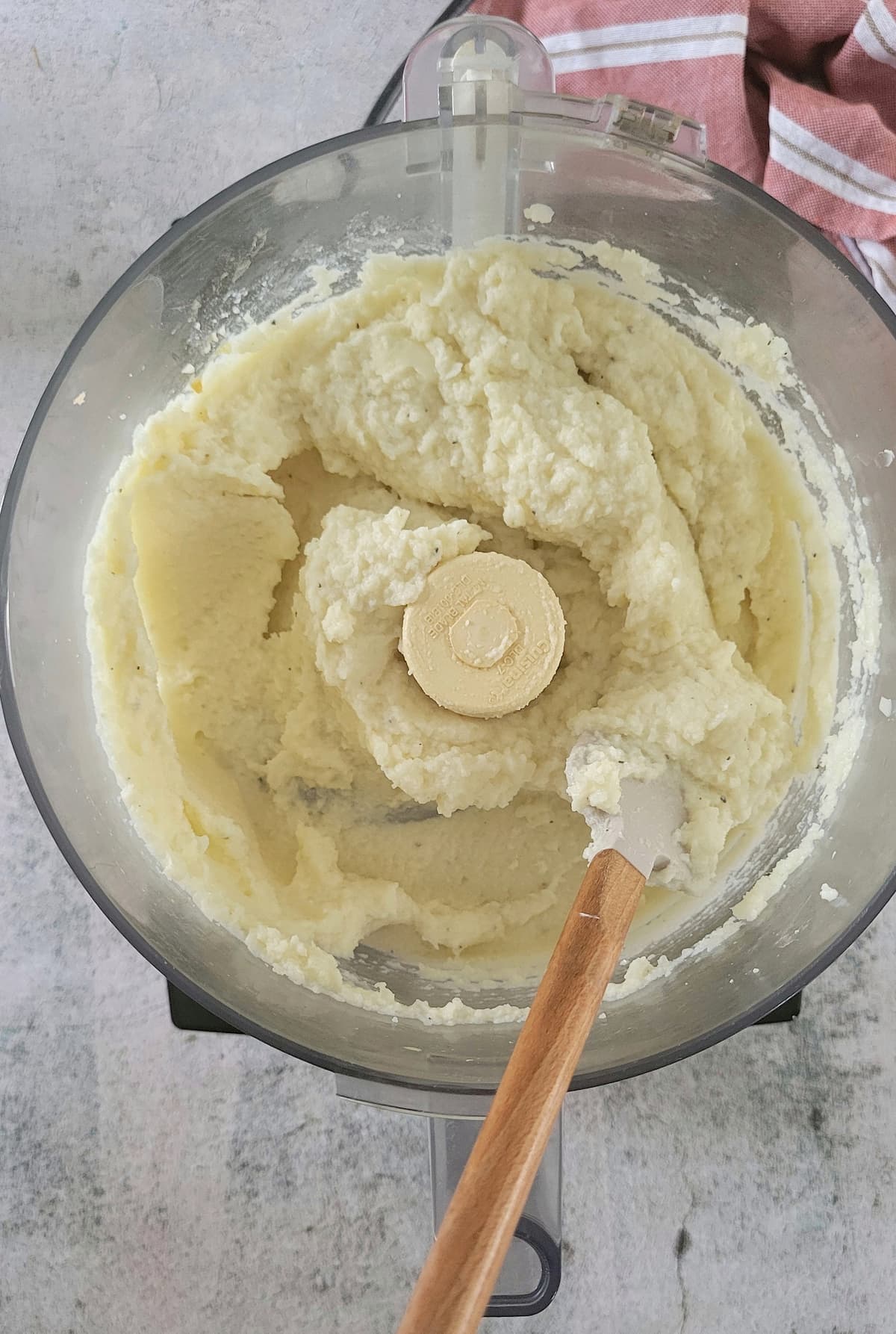 mashed cauliflower in a food processor with a rubber spatula