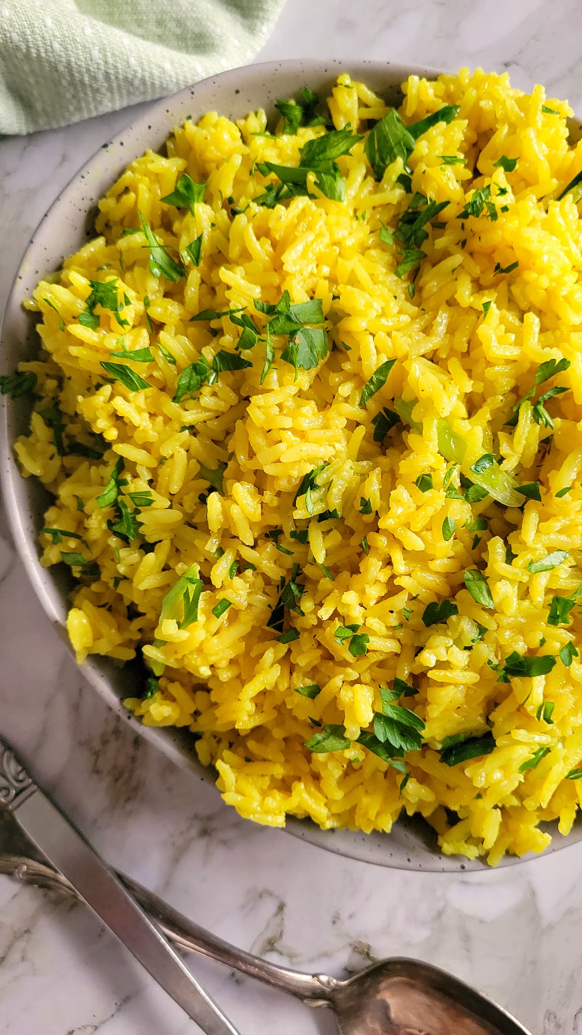 bowl of turmeric rice garnished with green onions and parsley