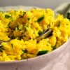 bowl of yellow rice with parsley and two spoons