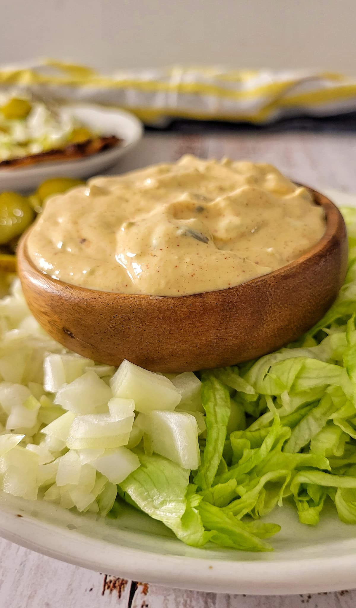 big mac sauce in a bowl on a plate with diced white onions and shredded lettuce